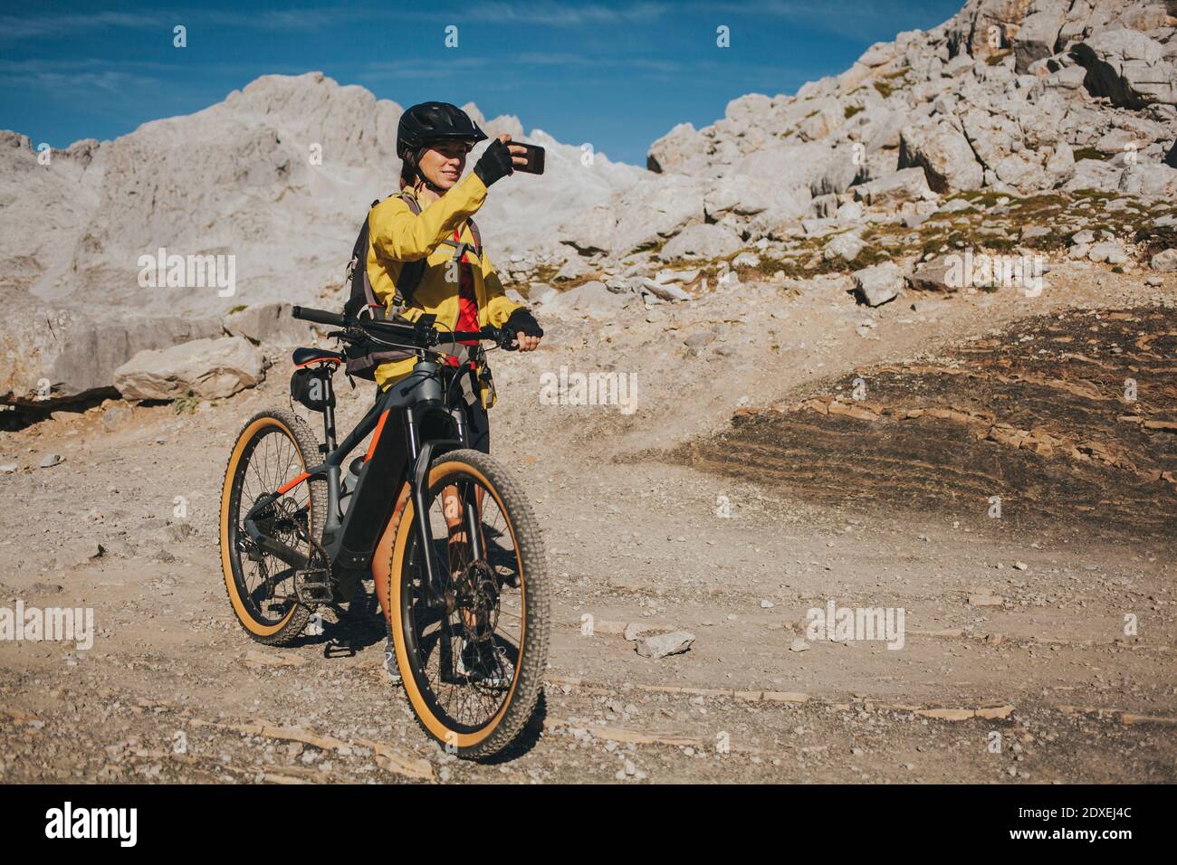 Ciclista femminile che fotografa al Parco Nazionale di Picos de Europa il giorno di sole, Cantabria, Spagna Foto Stock