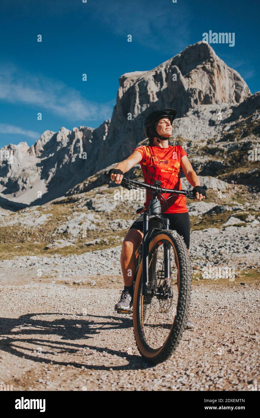 Sorridente ciclista femminile con occhi chiusi in bicicletta al Parco Nazionale Picos de Europa, Cantabria, Spagna Foto Stock
