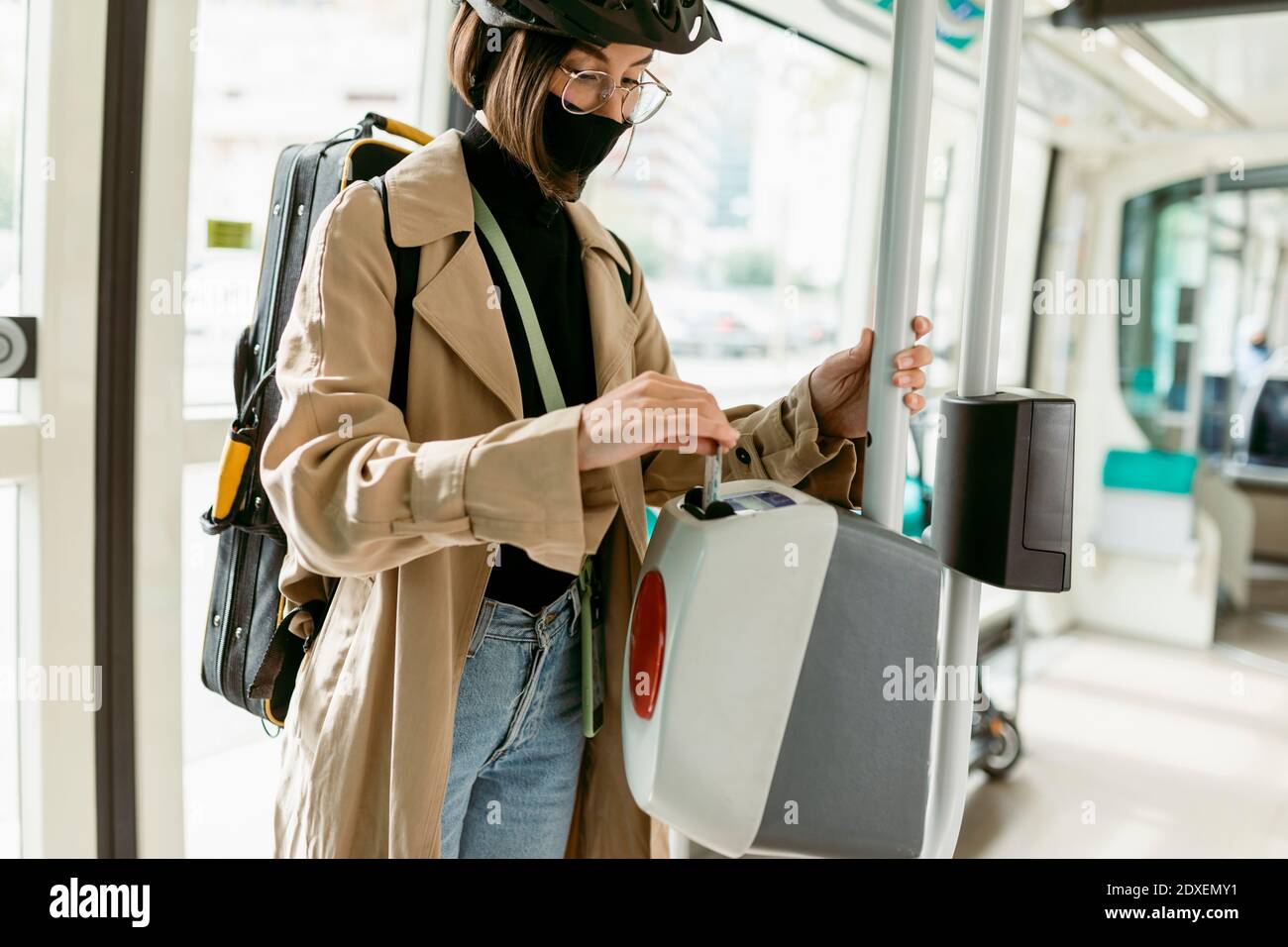 Donna che indossa maschera facciale e casco da ciclismo che mette il  biglietto macchina per la convalida dei biglietti mentre ci si trova in  tram Foto stock - Alamy