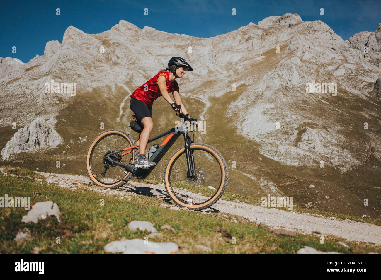 Ciclista femminile in bicicletta vicino alla montagna rocciosa al Parco Nazionale di Picos de Europa, Cantabria, Spagna Foto Stock