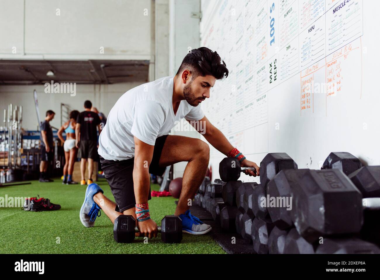 Atleta che prende i manubri in palestra Foto Stock