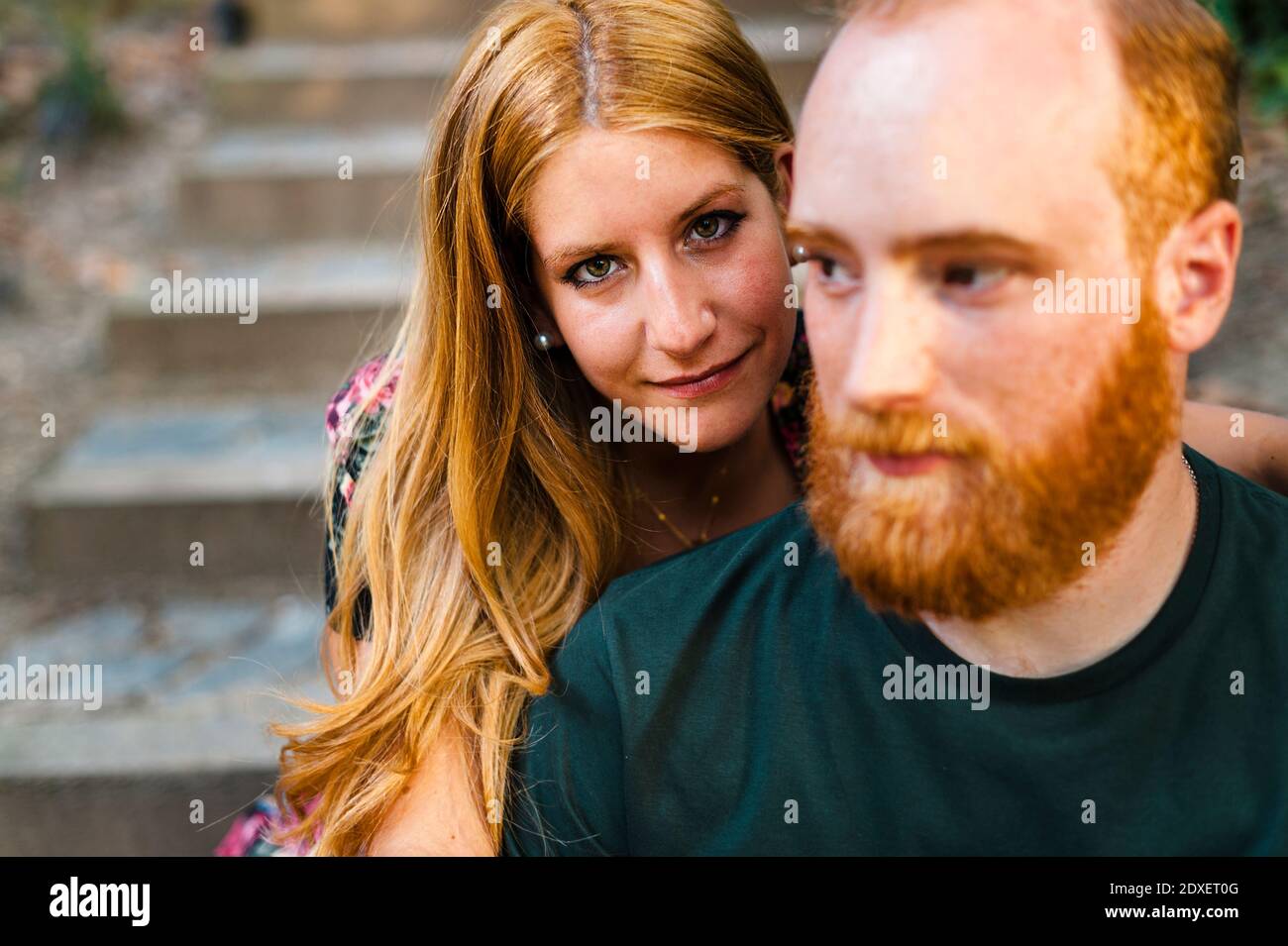 Coppia eterosessuale redhead seduta su gradini Foto Stock