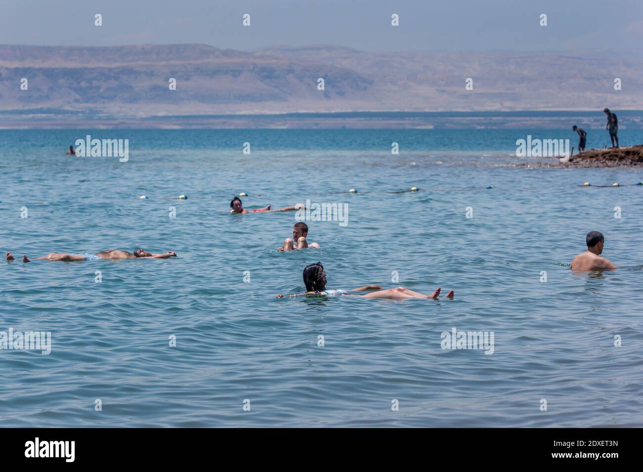 Turisti stranieri galleggiano sul Mar Morto in Giordania. Situato nella Jordan Rift Valley, l'acqua è 9.6 volte più salata dell'oceano. Foto Stock