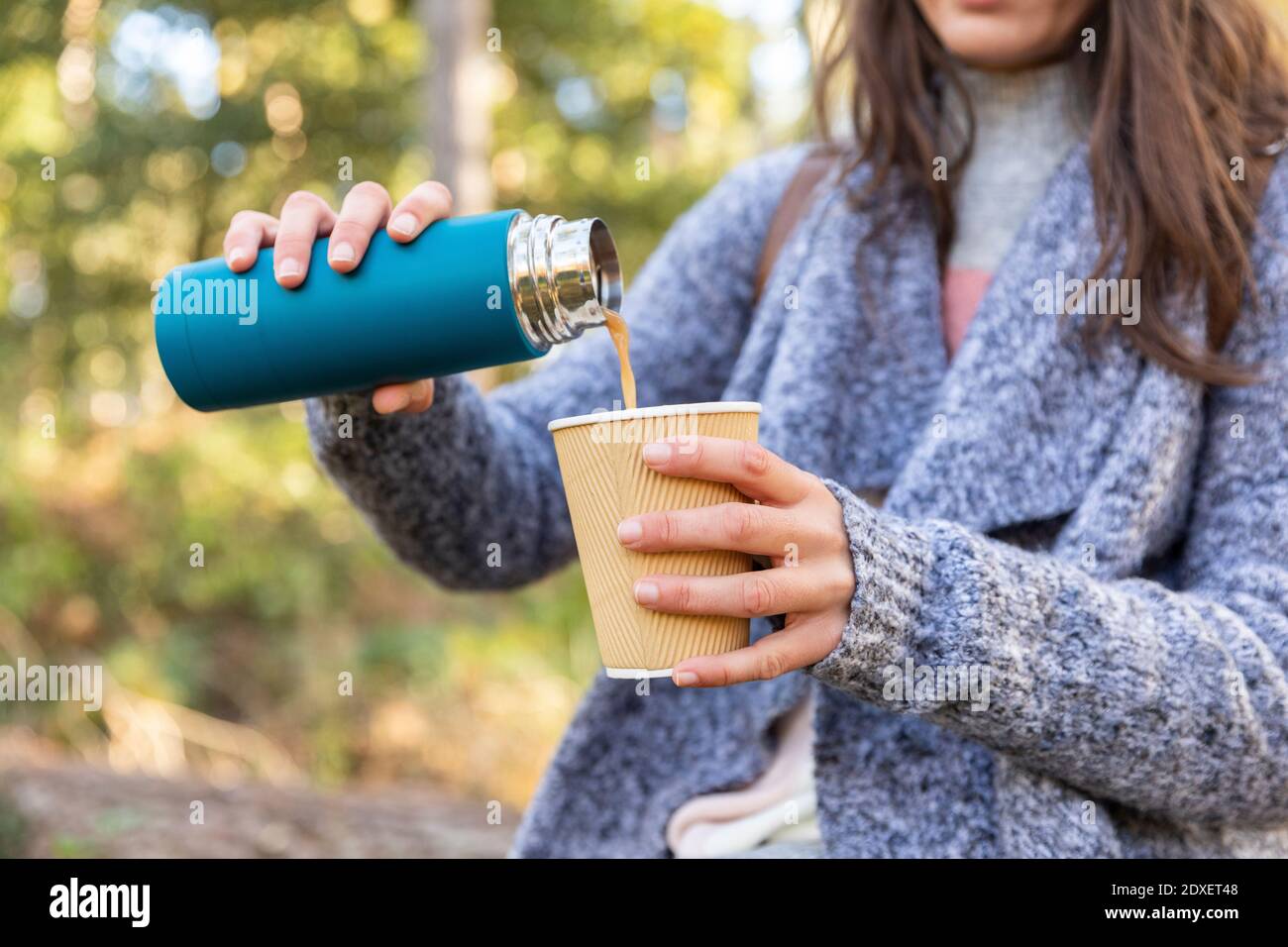 Donna che versa il tè dal contenitore isolato per bevande in una tazza monouso Nella foresta di Cannock Chase Foto Stock