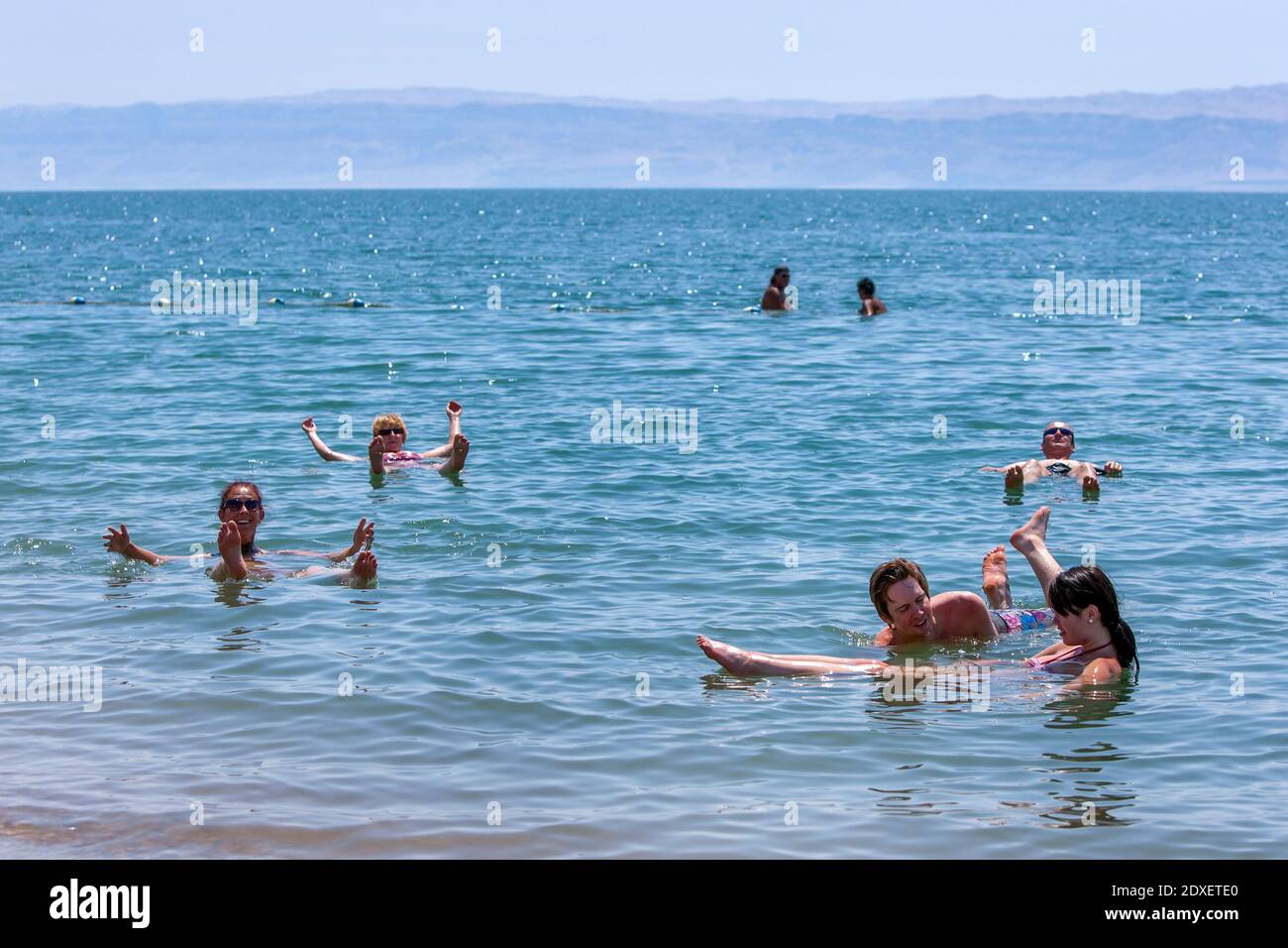 Turisti stranieri galleggiano sul Mar Morto in Giordania. Situato nella Jordan Rift Valley, l'acqua è 9.6 volte più salata dell'oceano. Foto Stock