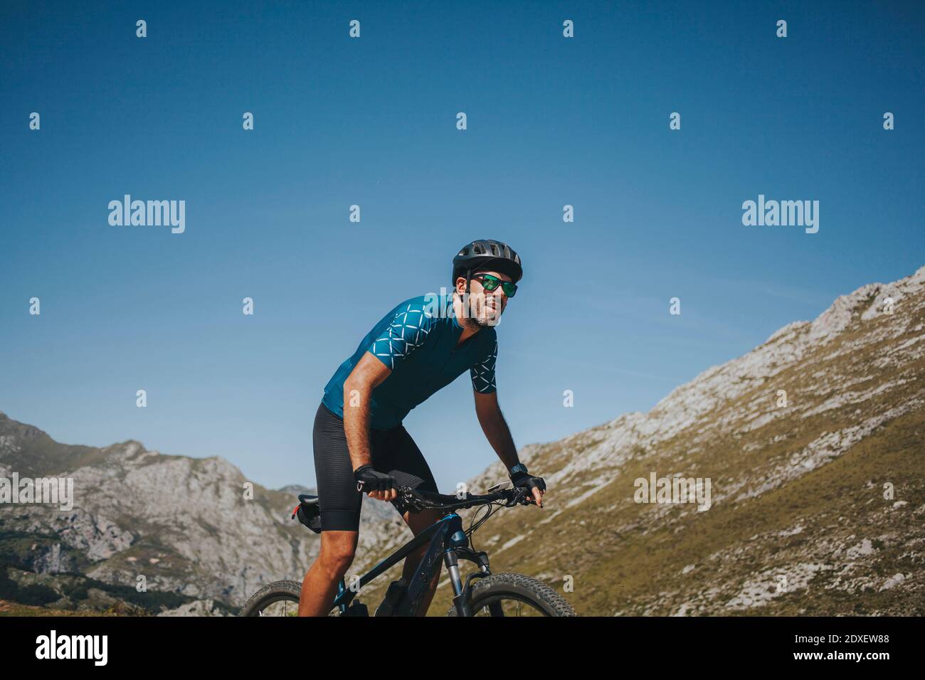 Ciclista maschile in mountain bike contro il cielo in giornata di sole, Parco Nazionale Picos de Europa, Asturie, Spagna Foto Stock