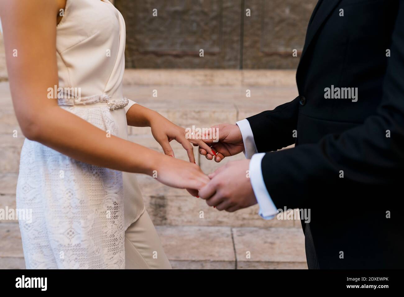 Giovane coppia sposata che tiene le mani dalla chiesa Foto Stock