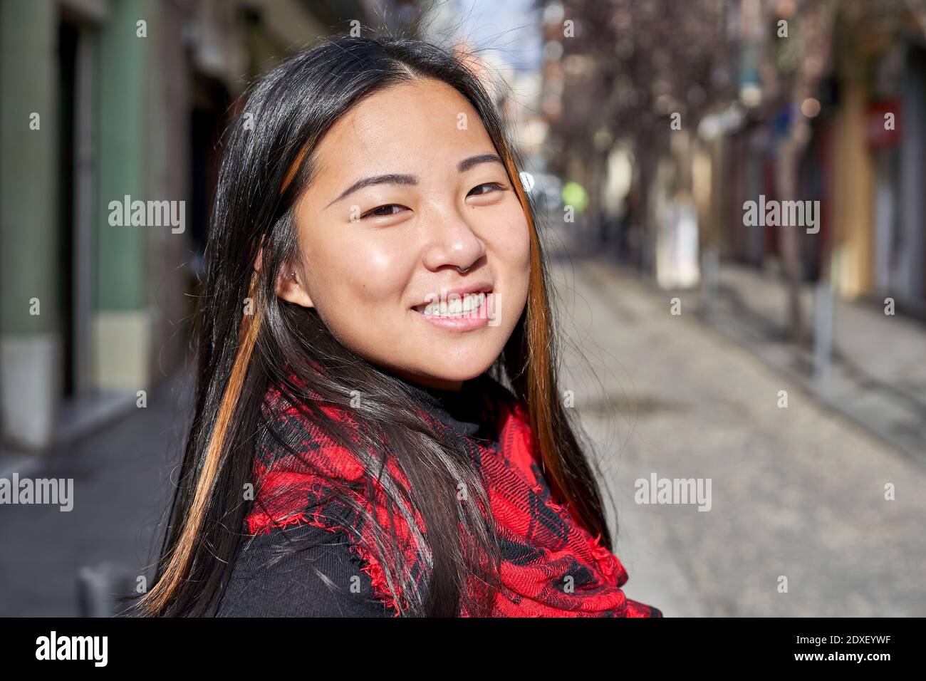 Donna che sorride mentre si trova in strada in città Foto Stock