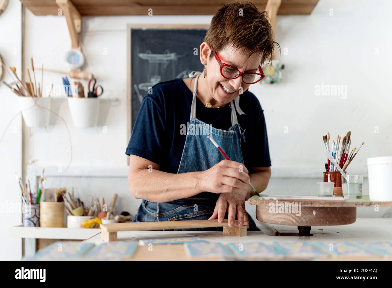 Sorridente proprietario pittura artigianale prodotto in ceramica officina Foto Stock