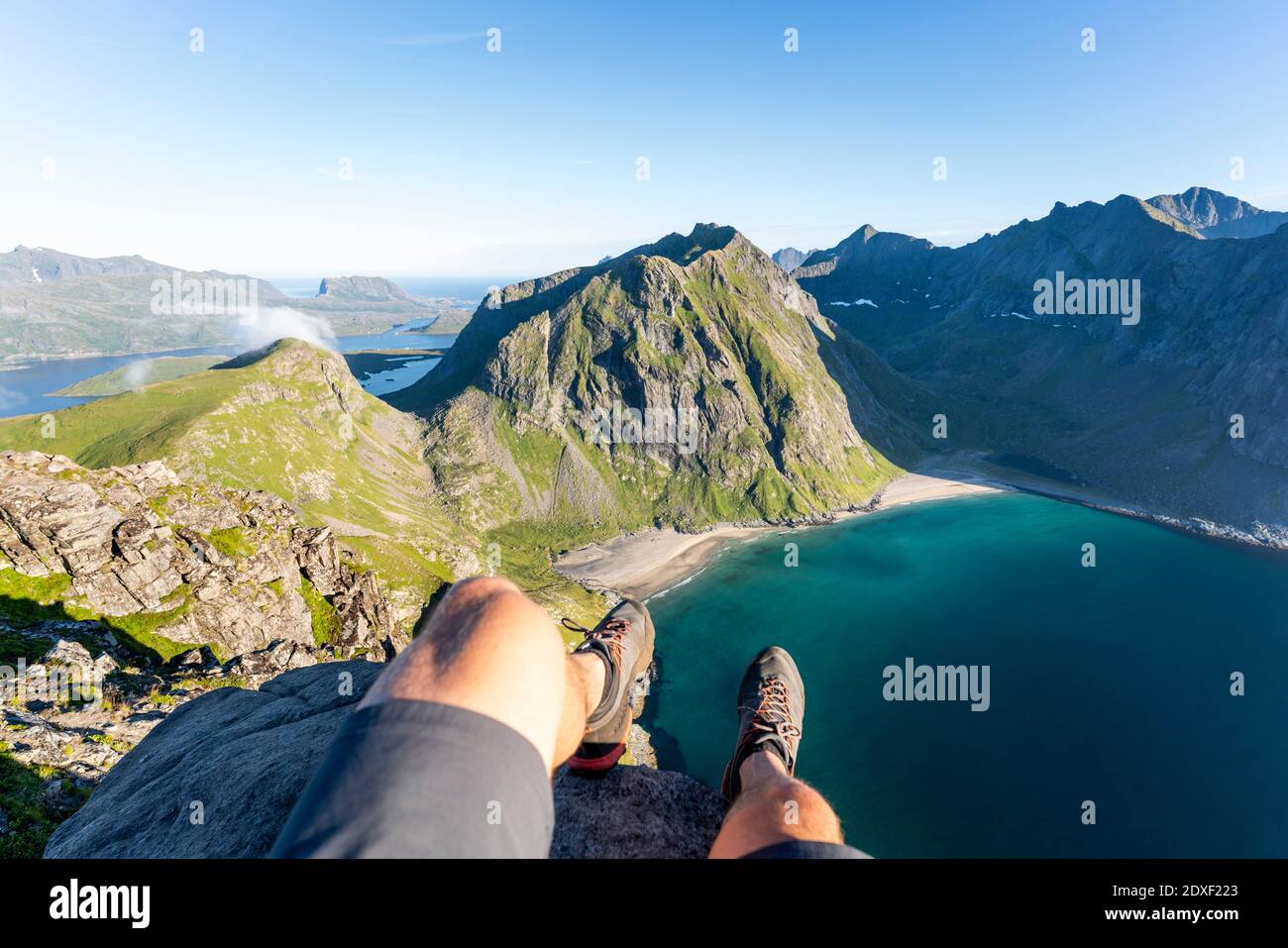 Uomo che indossa scarpe sportive seduto in montagna a Ryten, Lofoten, Norvegia Foto Stock