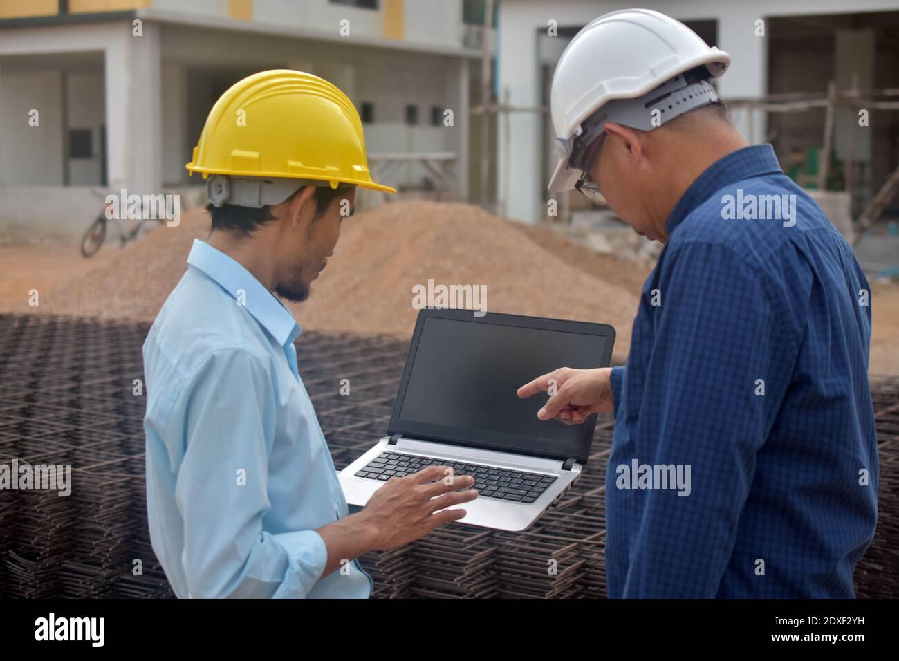 Due tecnici utilizzano la presentazione di notebook computer sul luogo di lavoro edificio edificio di background costruzione Foto Stock