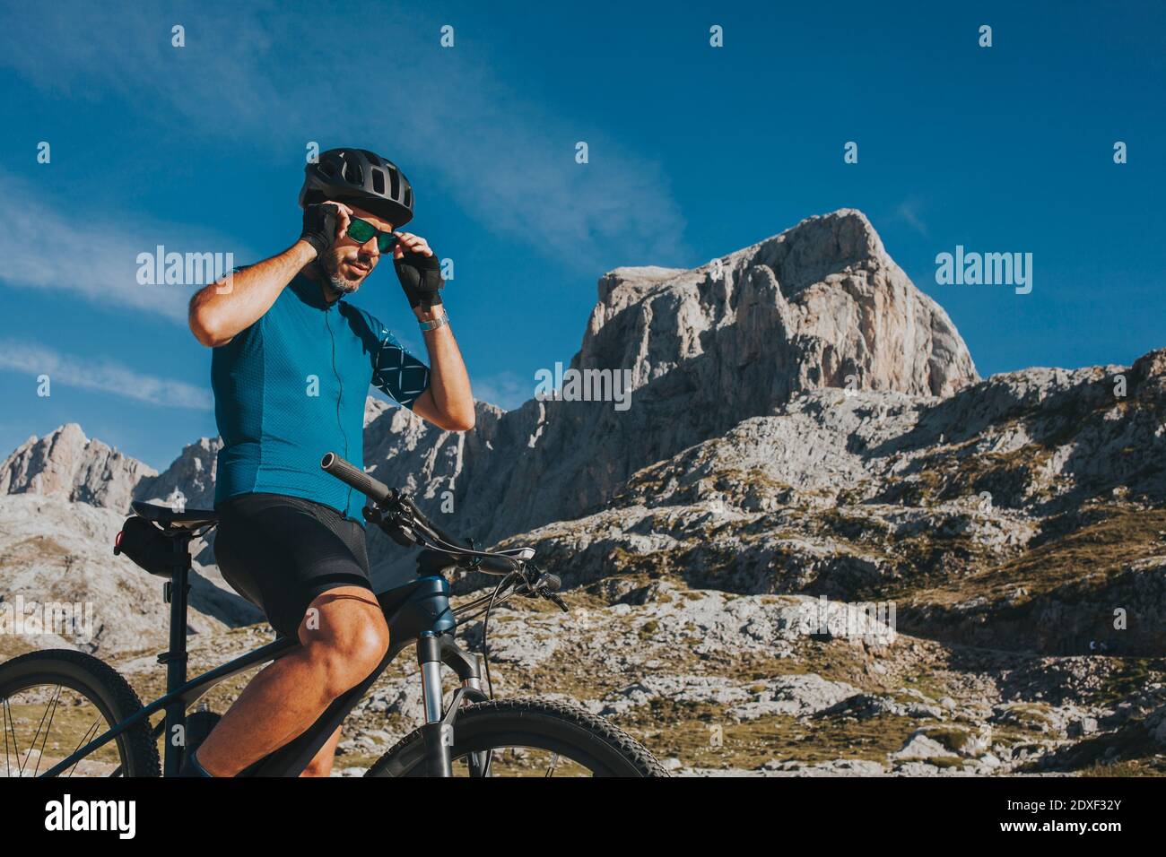 Ciclista maschile che indossa occhiali da sole al Parco Nazionale di Picos de Europa il giorno di sole, Cantabria, Spagna Foto Stock
