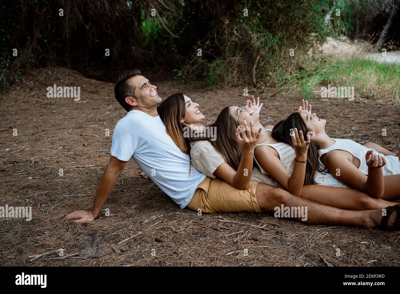 Una famiglia allegra che fa yoga mentre si sdraia di fila a. foresta durante la vacanza Foto Stock