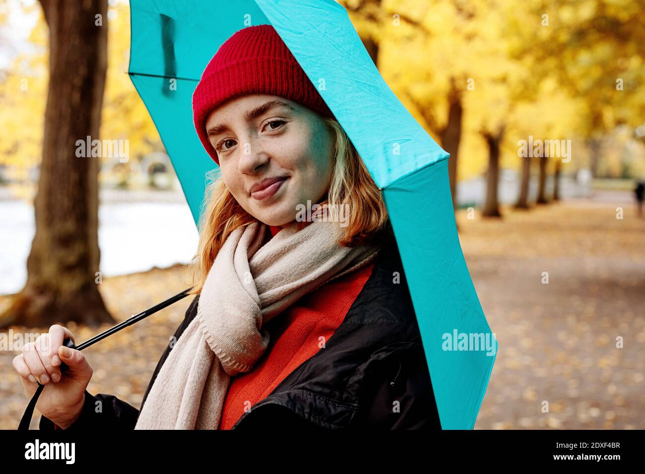 Bella ragazza adolescente che tiene l'ombrello mentre in piedi al parco Foto Stock