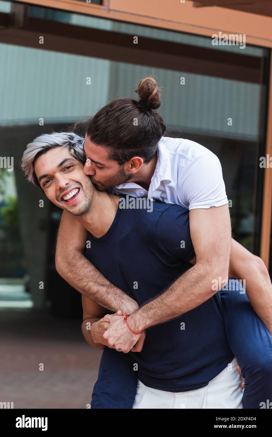 Uomo sorridente piggybacking gay partner in città Foto Stock