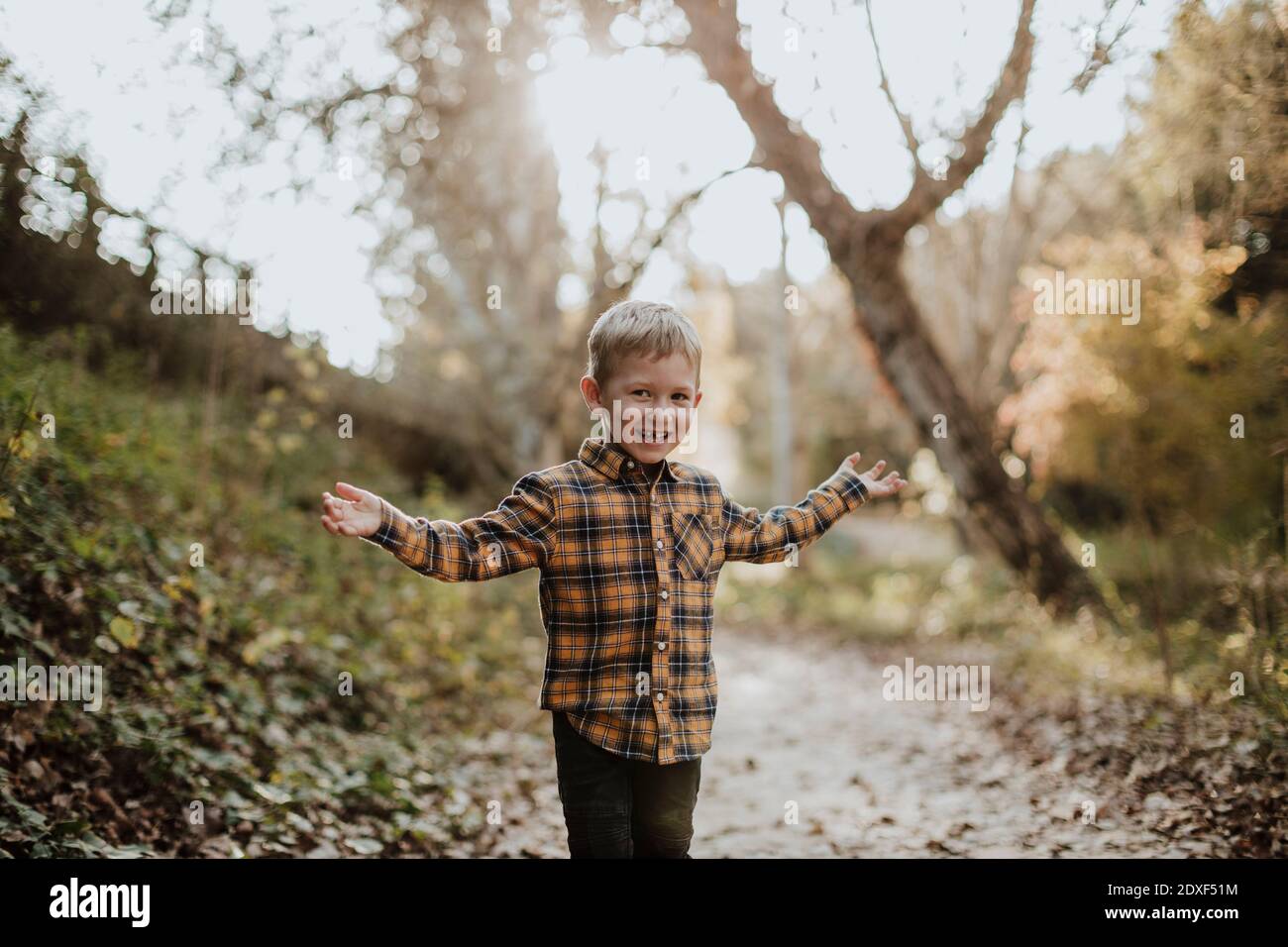 Ragazzo spensierato in piedi con le braccia distese in foresta Foto Stock
