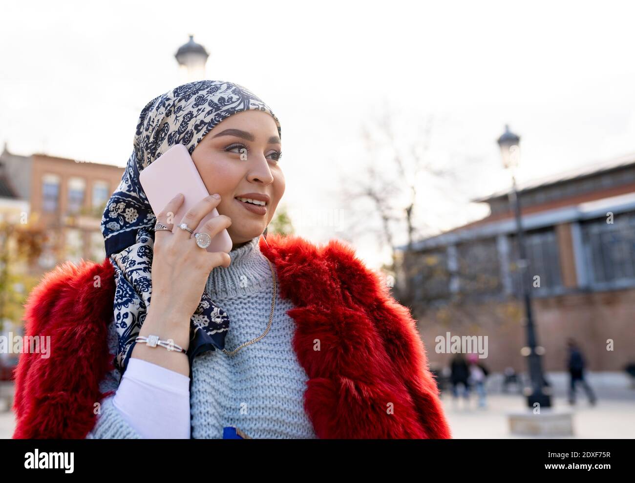 Bella donna con foulard e giacca in pelliccia che parla su cellulare telefono mentre si è in città Foto Stock