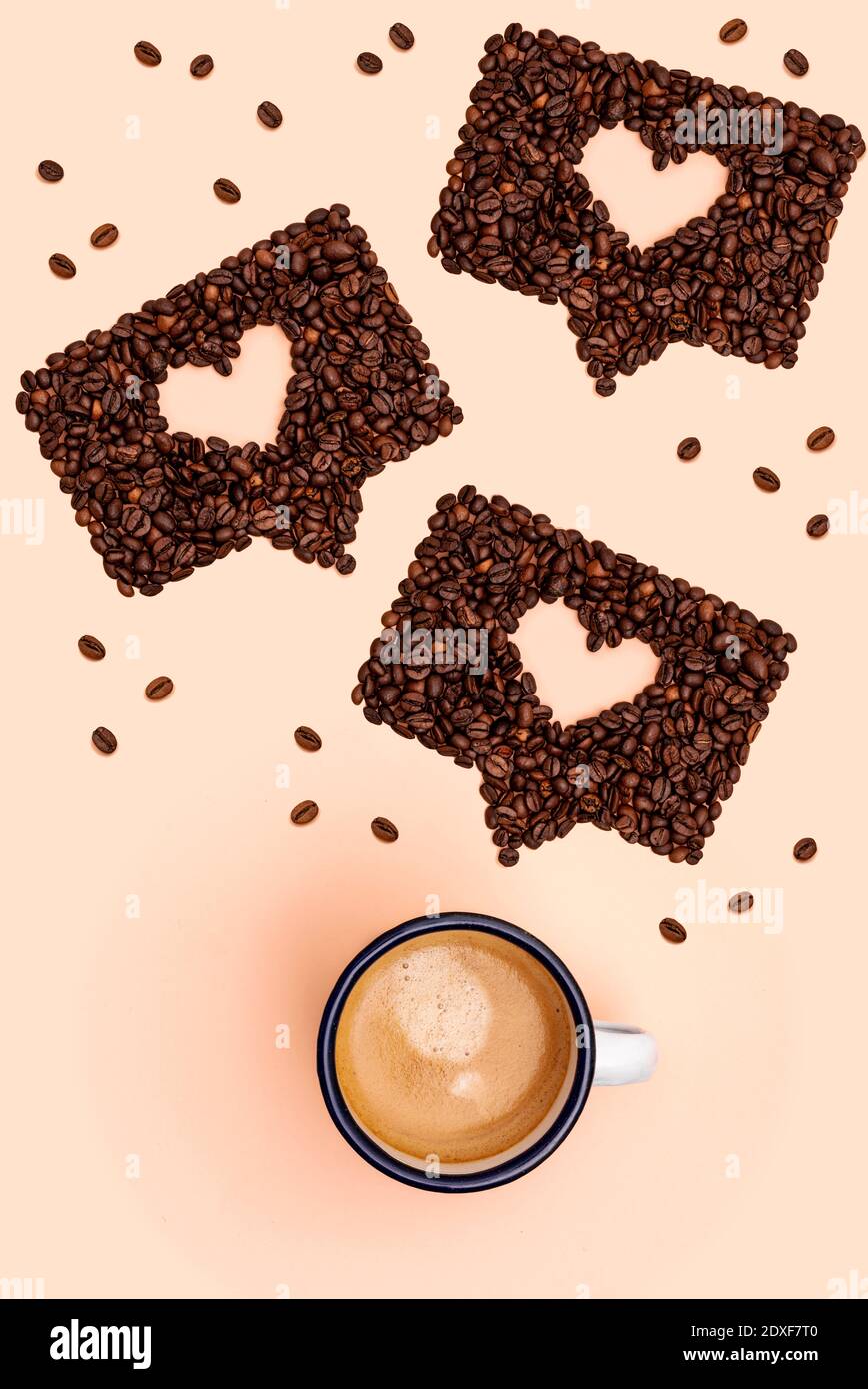 Shot studio di tazza di caffè e chicchi di caffè tostati disposti in forme di bolle di chat online Foto Stock