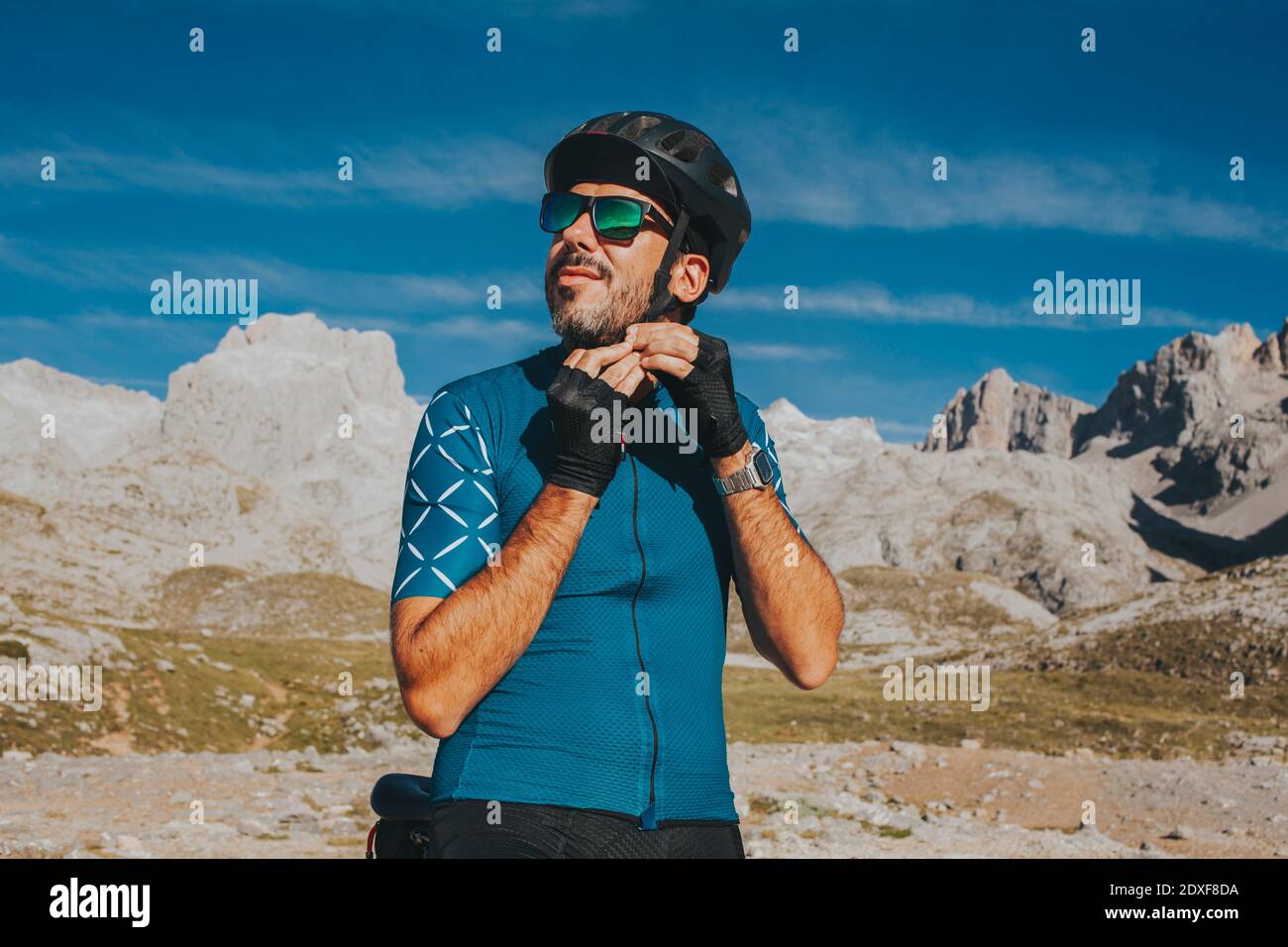 Ciclista che regola il casco da ciclismo al Parco Nazionale di Picos de Europa nella giornata di sole, Cantabria, Spagna Foto Stock