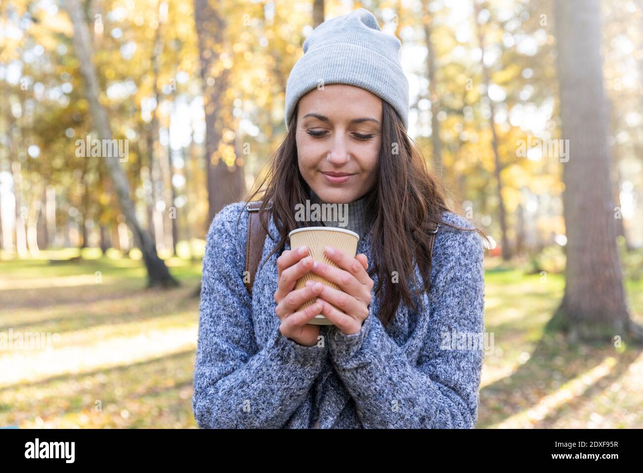 Hiker femminile che tiene la tazza del tè nel bosco di Cannock Chase durante inverno Foto Stock