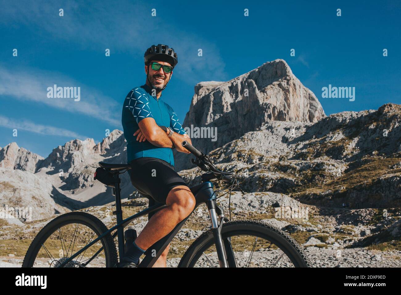 Ciclista di montagna sorridente con armi attraversate al Parco Nazionale Picos de Europa Cantabria, Spagna Foto Stock