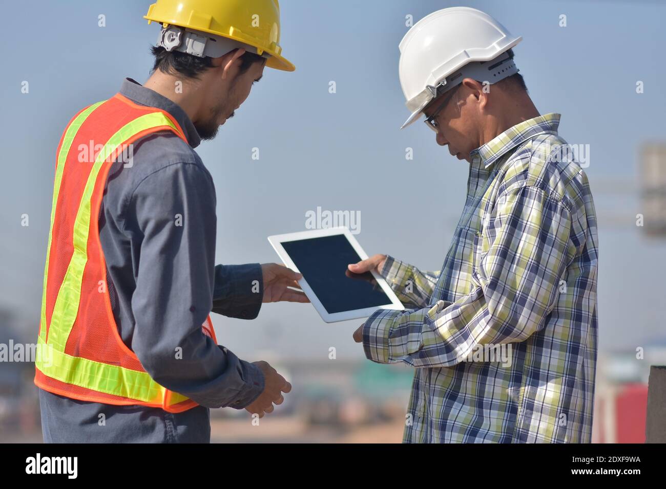 Due tecnici che utilizzano la tecnologia tablet per il controllo della costruzione dei lavori di ispezione e. gestione del progetto di pianificazione parlante Foto Stock