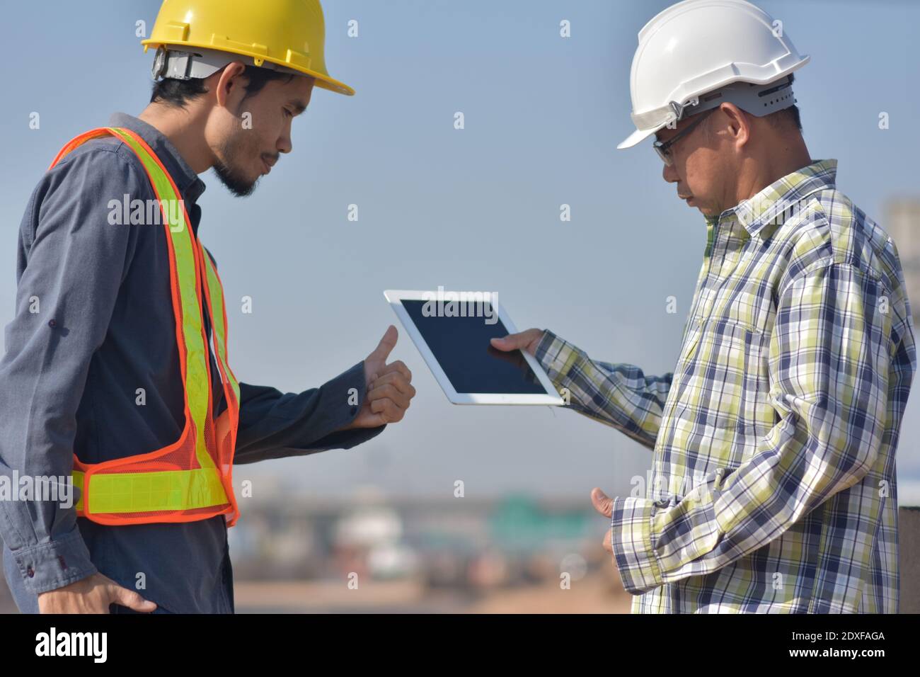 Due tecnici che utilizzano la tecnologia tablet per il controllo della costruzione dei lavori di ispezione e. gestione del progetto di pianificazione parlante Foto Stock
