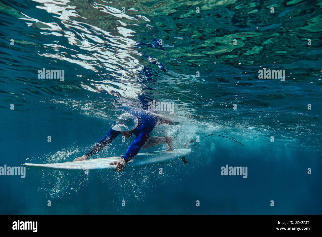 Subacquea maschile surfista con surf in mare alle Maldive Foto Stock