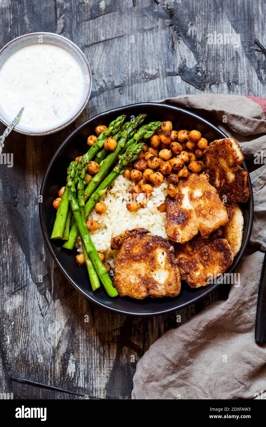 Salsa e ciotola di riso con ceci, gambi di asparagi e formaggio halloumi fritto Foto Stock