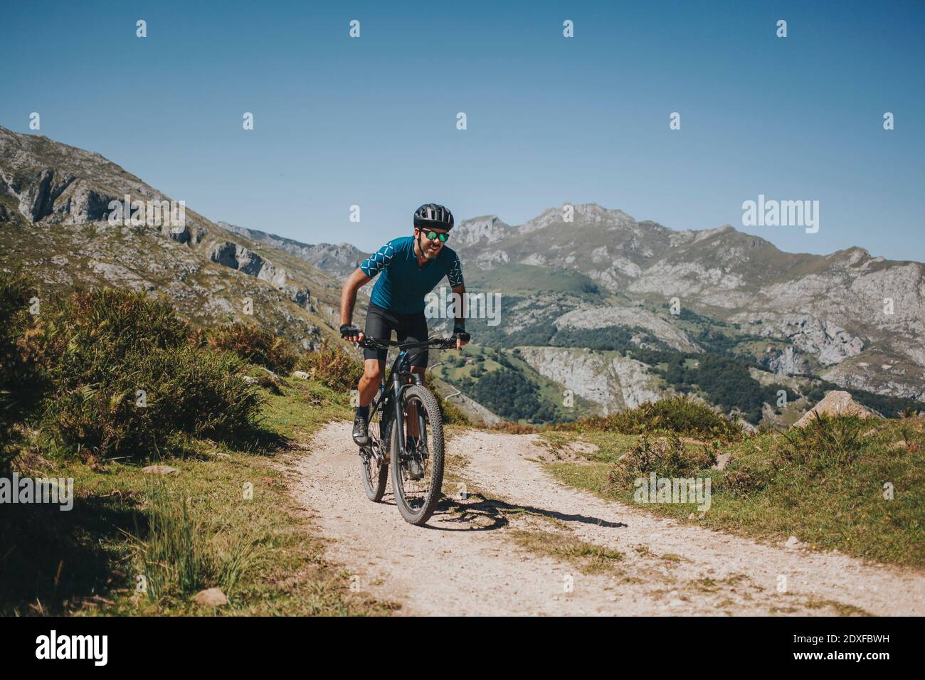 Ciclista maschile a cavallo mountain bike su sentiero contro il cielo, Parco Nazionale Picos de Europa, Asturie, Spagna Foto Stock