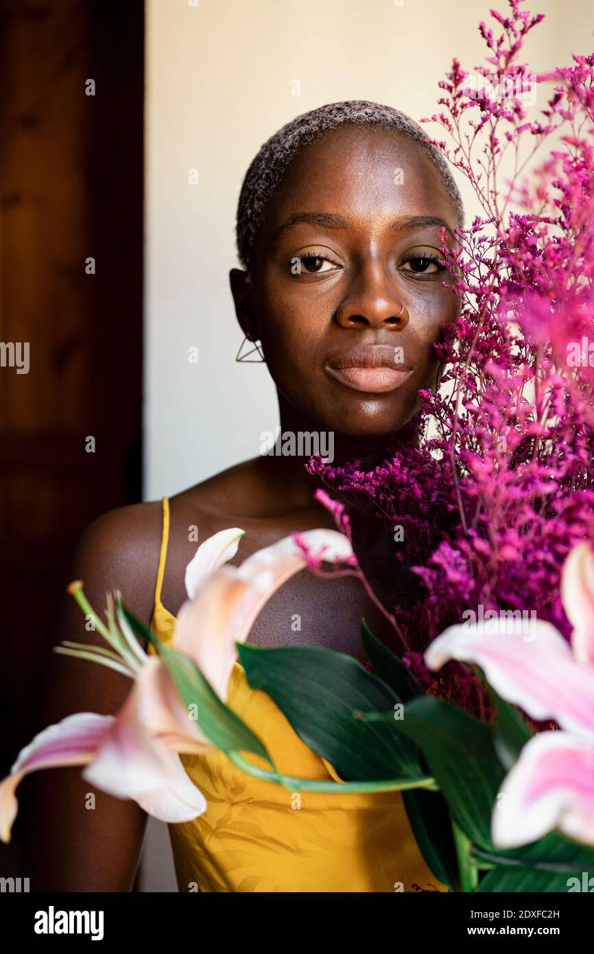 Donna mid adulta che tiene fiori a casa Foto Stock