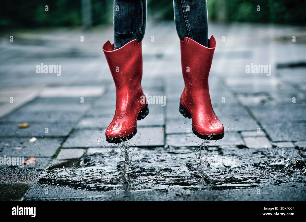 Piedi di bambina che indossa stivali in gomma che saltano su piccoli puddle  Foto stock - Alamy