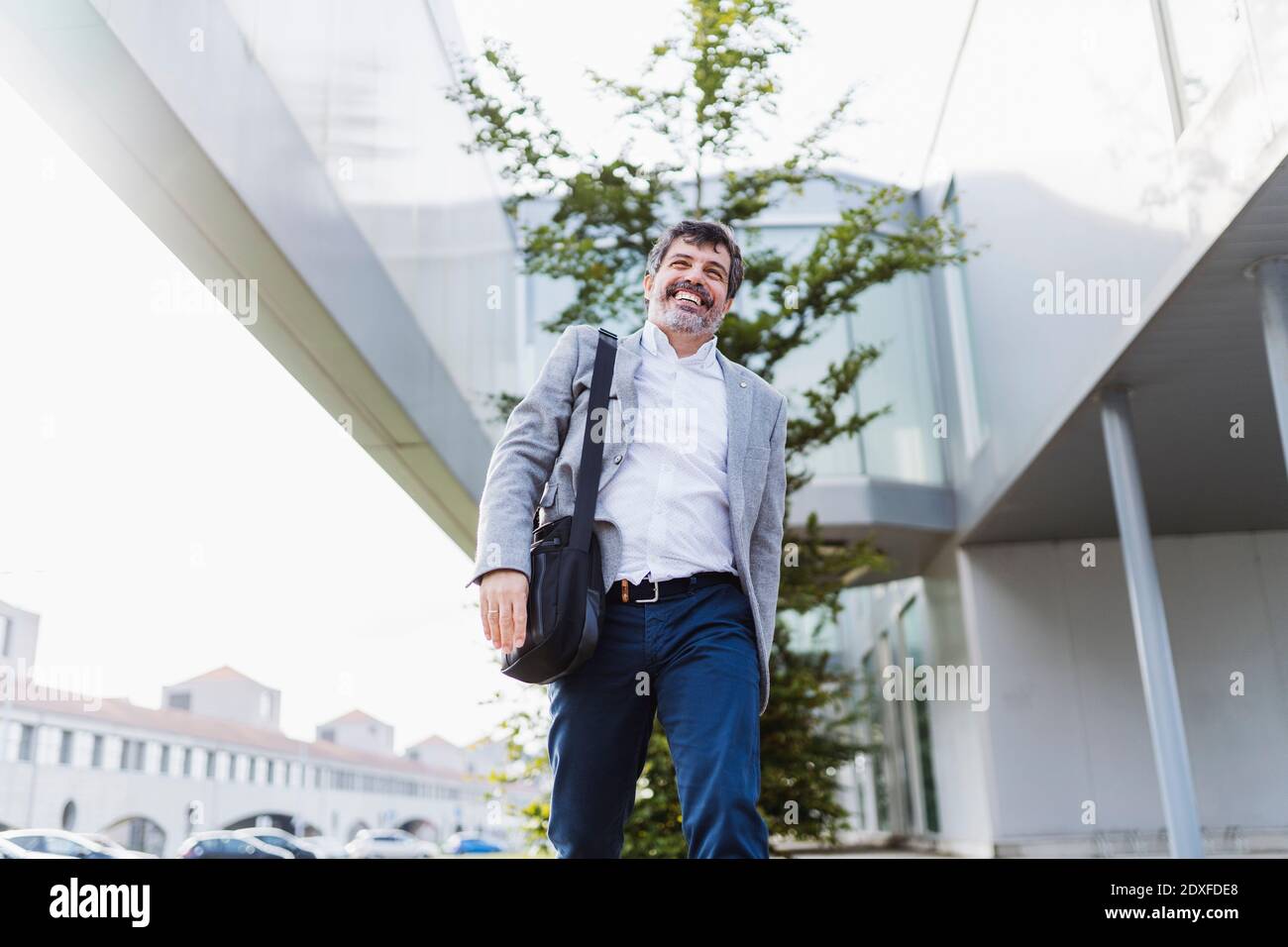 Uomo d'affari felice con borsa che cammina attraverso l'edificio dell'ufficio Foto Stock