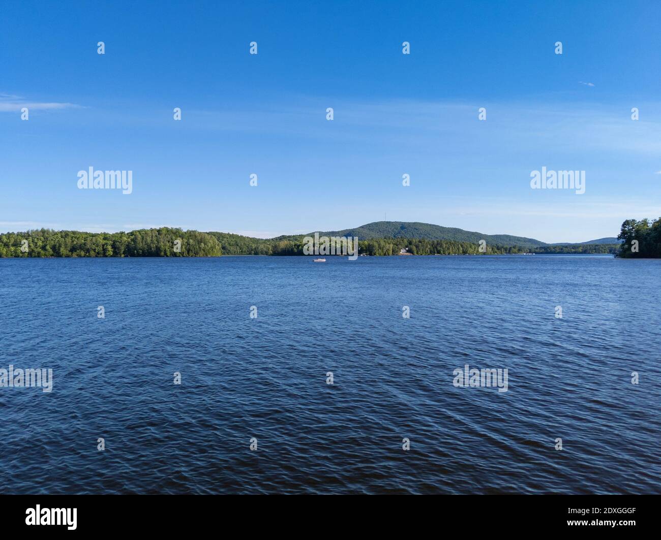 Piccola barca sul lago Canada vista con foresta e montagne al bordo del lago in estate Foto Stock