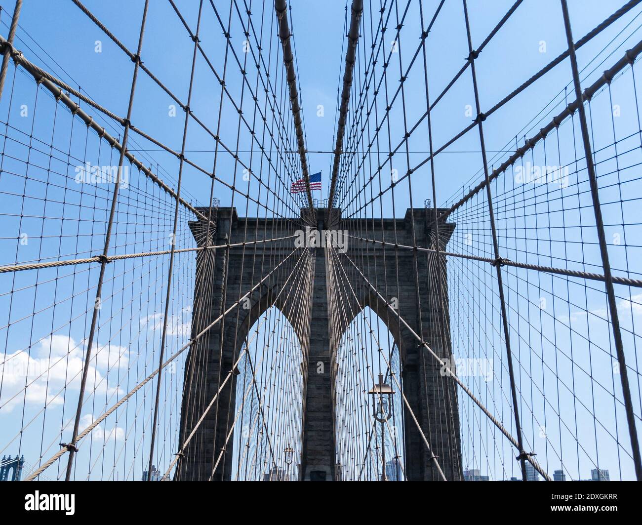 Ponte di Brooklyn in un luminoso giorno estivo a New York con Bandiera americana sventolando nel vento Foto Stock