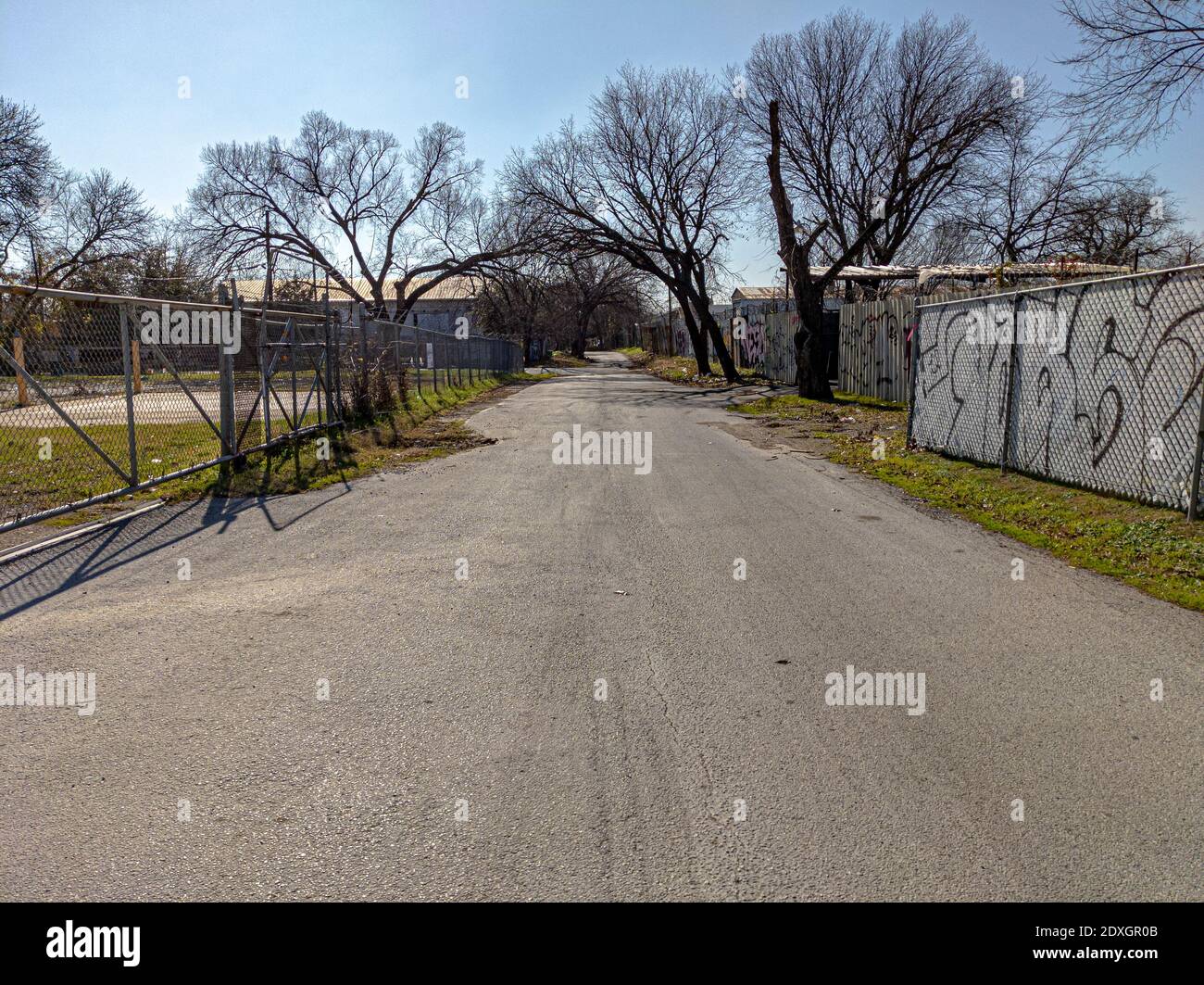 Vuota strada posteriore a Dallas, Texas, con edifici abbandonati e graffiti sulla recinzione Foto Stock