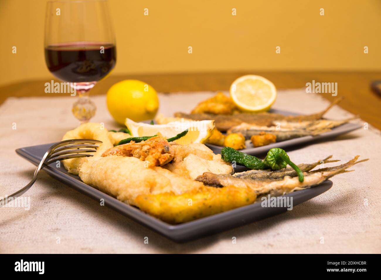primo piano di piatti con pesce fritto dorato e vino Foto Stock