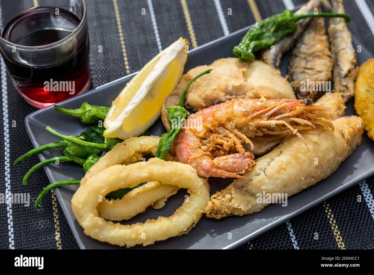 primo piano di piatti con pesce fritto dorato e vino Foto Stock