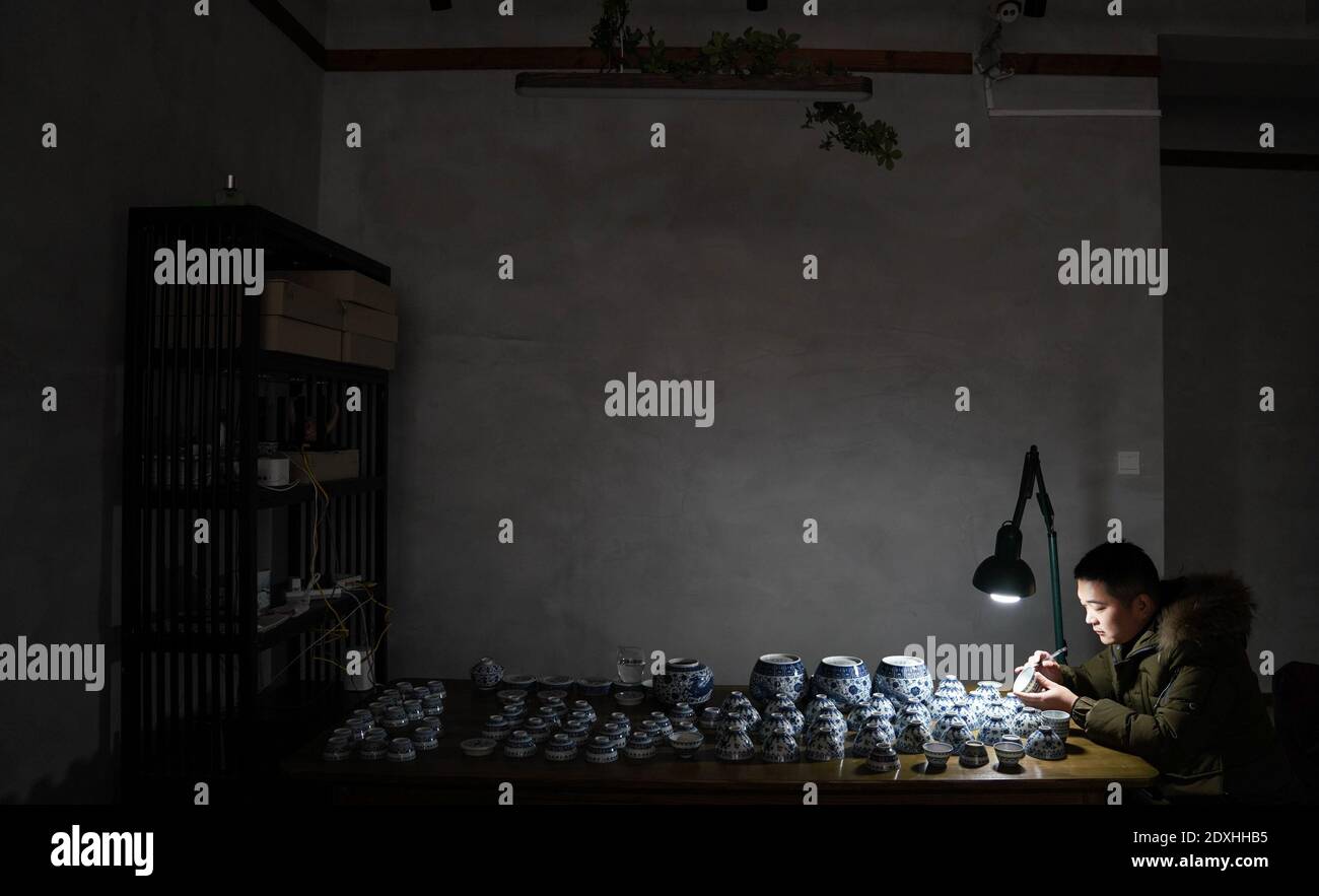 Jingdezhen, provincia cinese di Jiangxi. 23 dicembre 2020. Un membro dello staff di Kuaixueshiqing, un team di produzione artigianale di porcellane, esamina i prodotti a Jingdezhen, provincia di Jiangxi, nella Cina orientale, il 23 dicembre 2020. Il team Kuaixueshiqing con sede a Jingdezhen, conosciuta come la capitale cinese della porcellana, produce ciotole e tazze di porcellana combinando tecniche multiple. Il team ha più di 10 varietà di prodotti, favoriti sia da consumatori nazionali che stranieri. Credit: HU Chenhuan/Xinhua/Alamy Live News Foto Stock