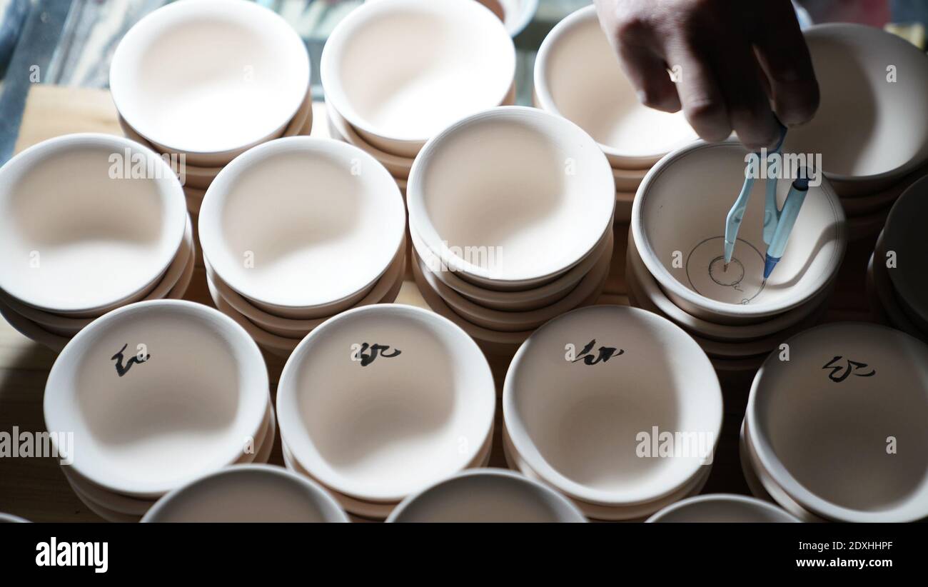Jingdezhen, provincia cinese di Jiangxi. 23 dicembre 2020. Un membro dello staff di Kuaixueshiqing, un team di produzione artigianale di porcellane, si occupa di un lavoro di porcellana a Jingdezhen, nella provincia di Jiangxi, nella Cina orientale, il 23 dicembre 2020. Il team Kuaixueshiqing con sede a Jingdezhen, conosciuta come la capitale cinese della porcellana, produce ciotole e tazze di porcellana combinando tecniche multiple. Il team ha più di 10 varietà di prodotti, favoriti sia da consumatori nazionali che stranieri. Credit: HU Chenhuan/Xinhua/Alamy Live News Foto Stock