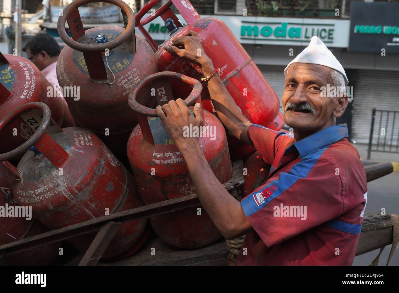 Una fornitura di gas con il suo carrello pieno di bombole di gas di cottura a Mumbai, India Foto Stock