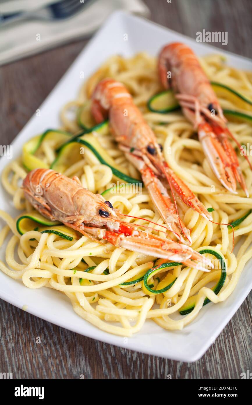 Tagliatelle fatte a mano con gamberi e zucchine in un piatto. Foto Stock
