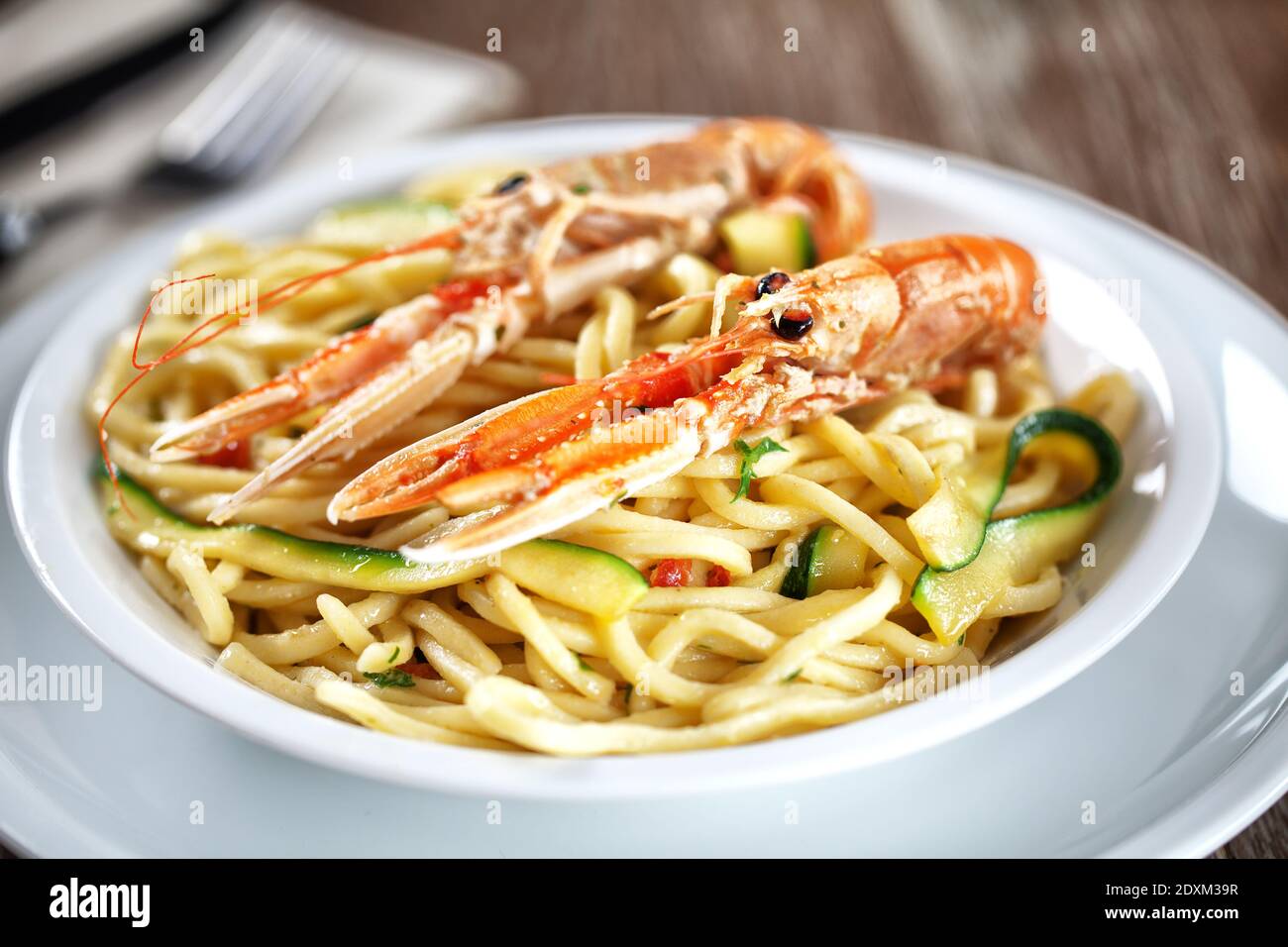 Tagliatelle fatte a mano con gamberi e zucchine in un piatto. Foto Stock