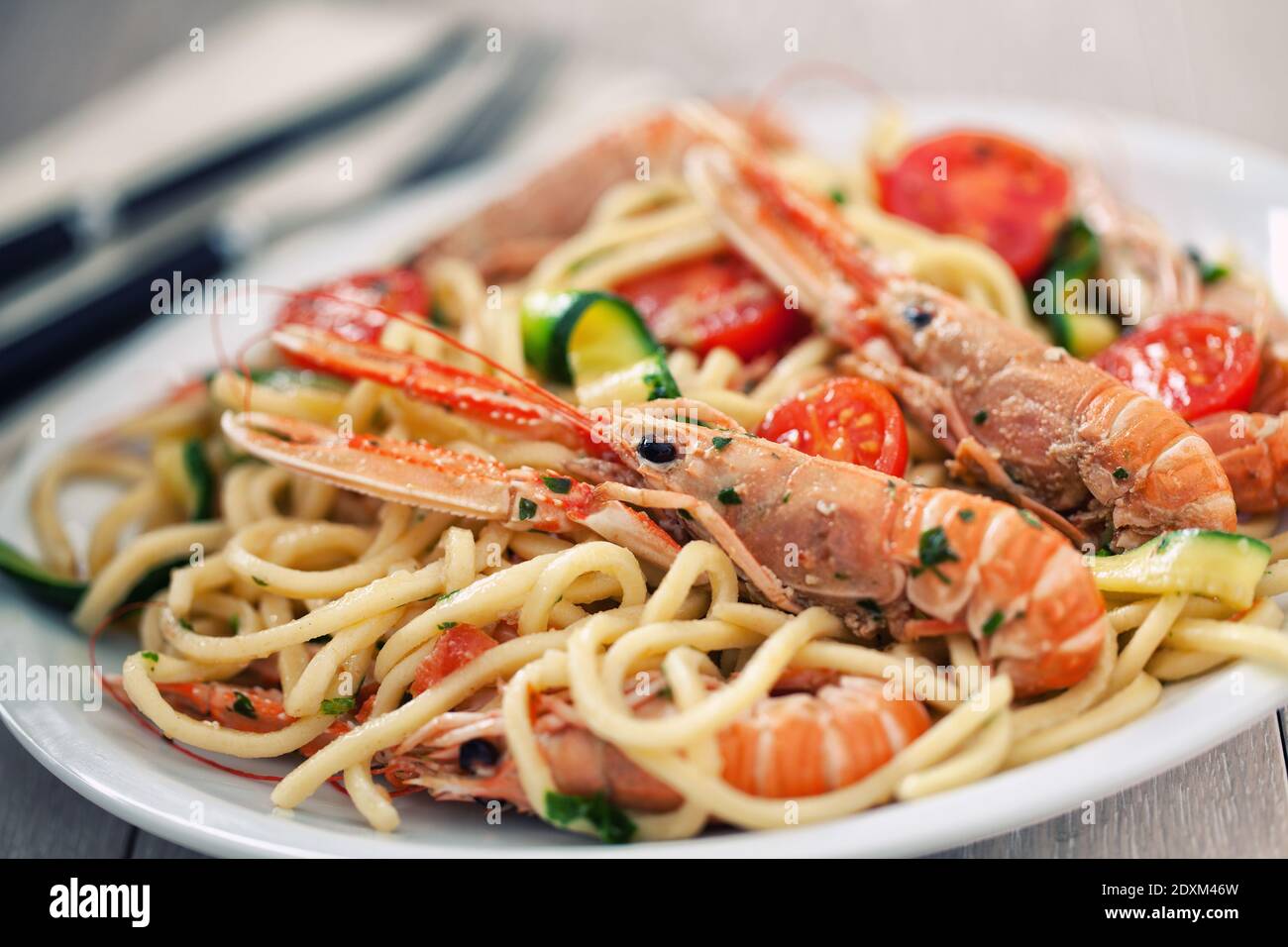 Tagliatelle fatte a mano con gamberi e zucchine in un piatto. Foto Stock