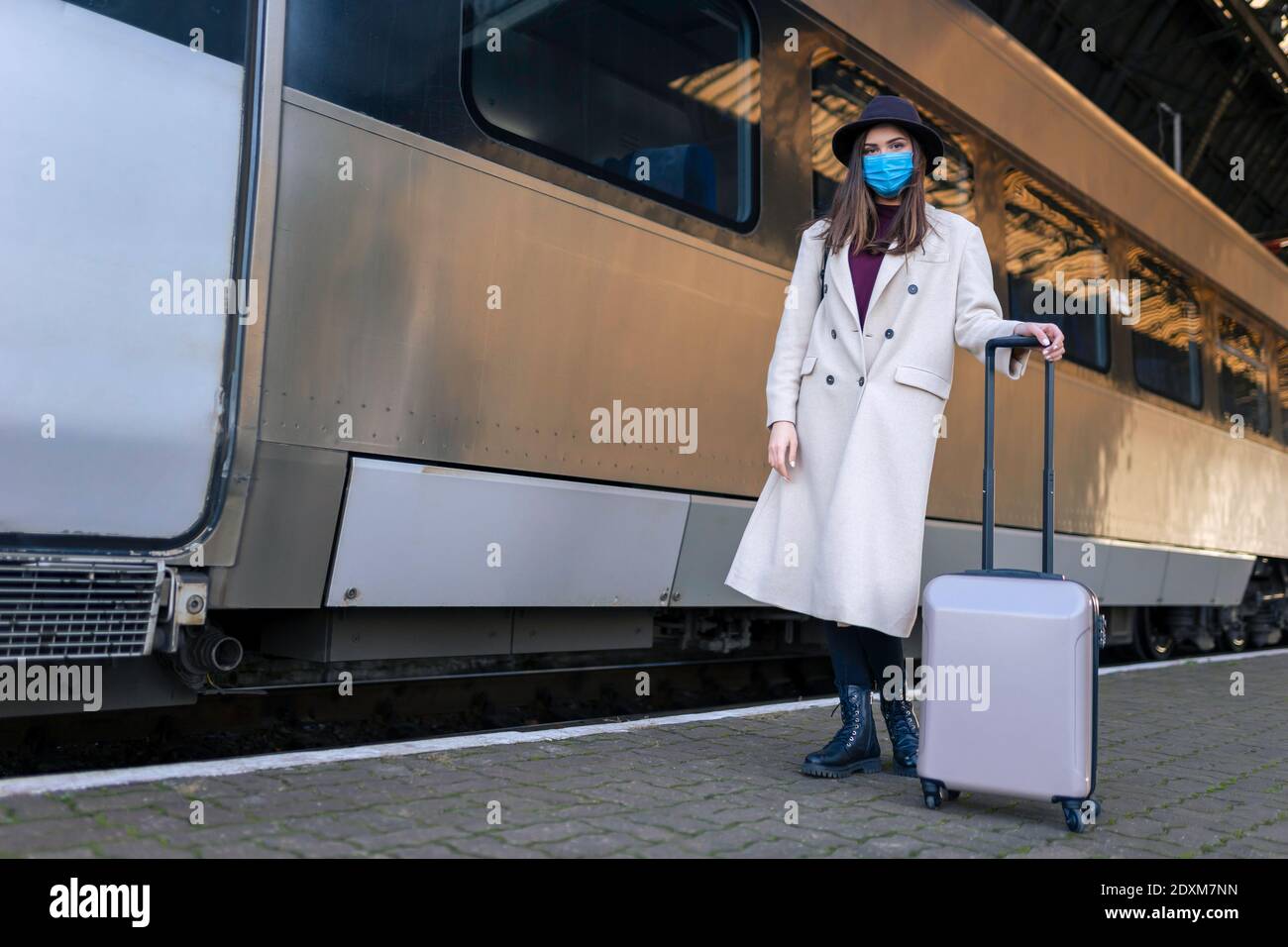 Donna turistica mascherata alla stazione ferroviaria. Turismo durante un concetto pandemico. Misure di prevenzione dei virus nei trasporti pubblici Foto Stock