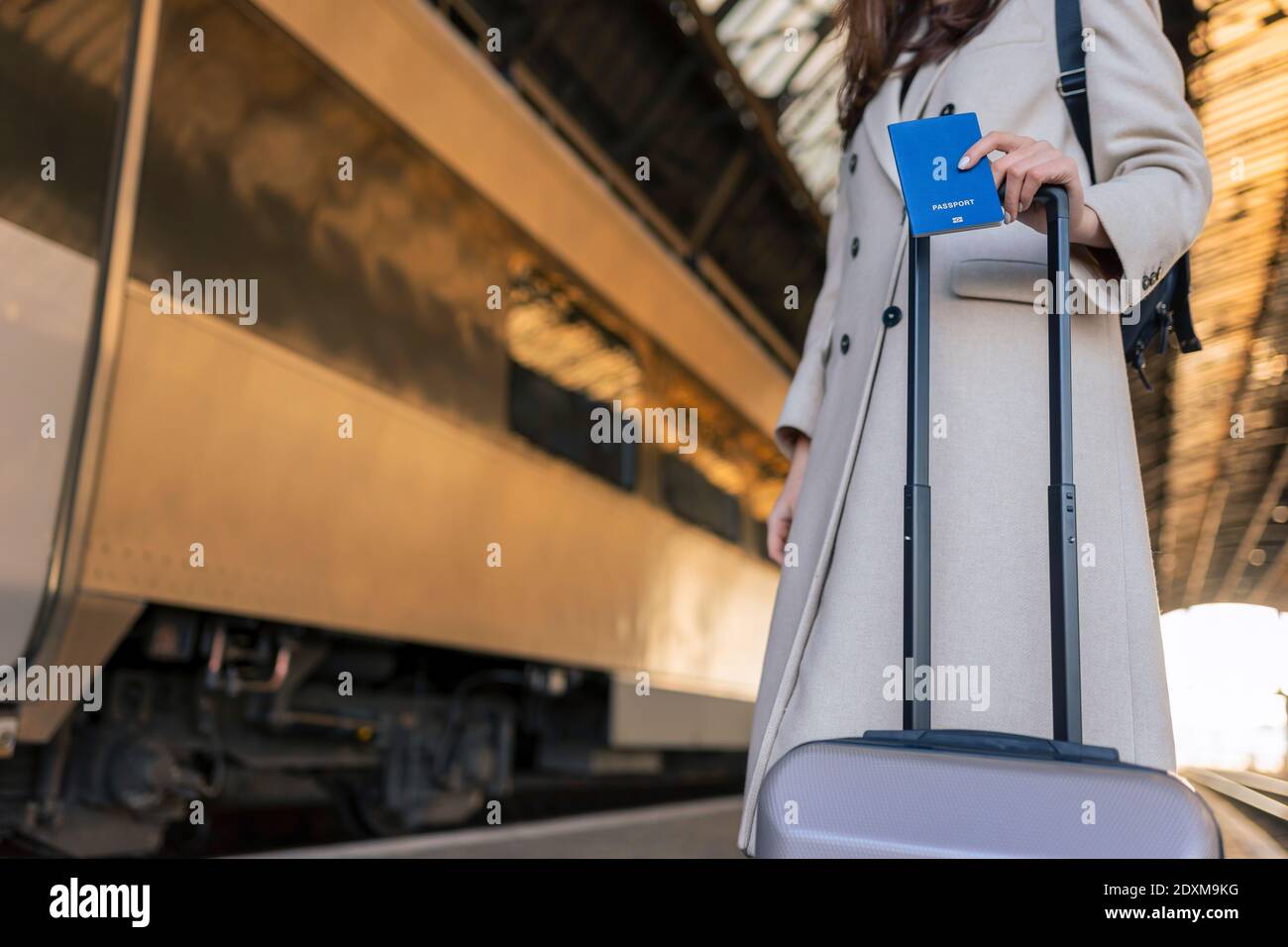 Passeggero femminile con valigia e passaporto in mano alla stazione ferroviaria. Viaggiatore in attesa di salire a bordo del treno Foto Stock