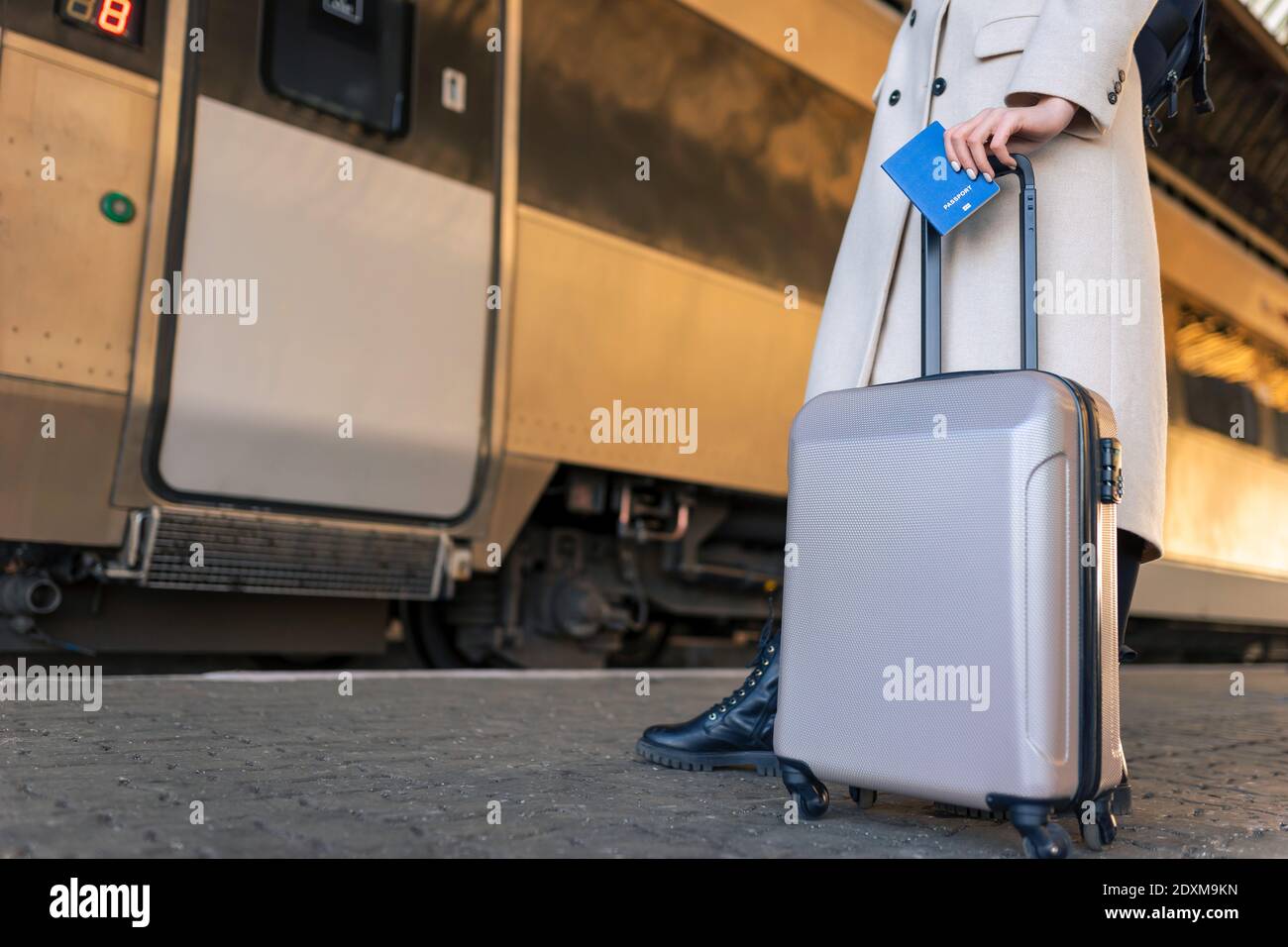Passeggero femminile con valigia e passaporto in mano alla stazione ferroviaria. Viaggiatore in attesa di salire a bordo del treno Foto Stock