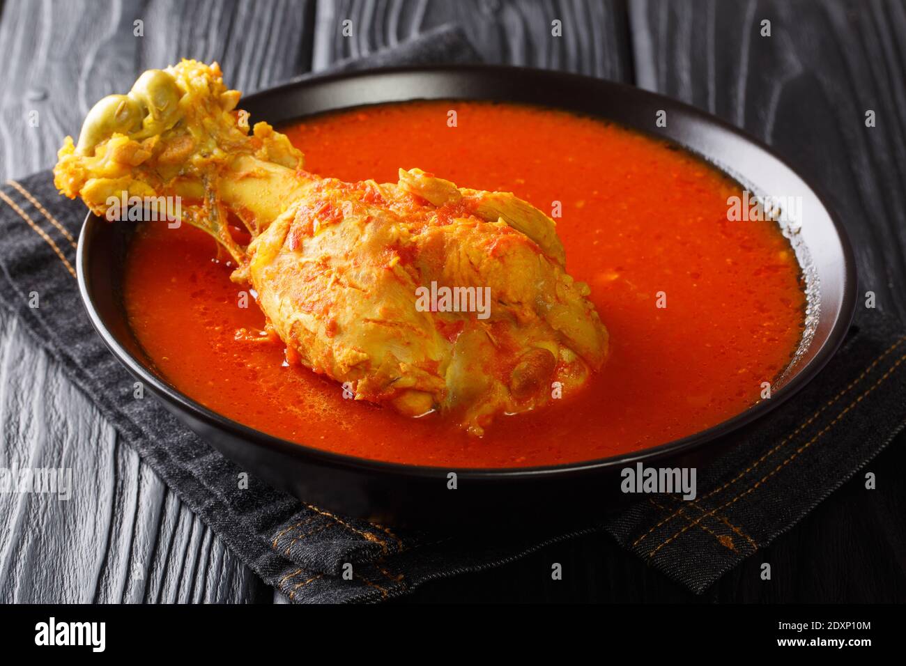 Zuppa di tacchino dell'America centrale in brodo vegetale rosso con spezie da vicino in un recipiente sul tavolo. Orizzontale Foto Stock