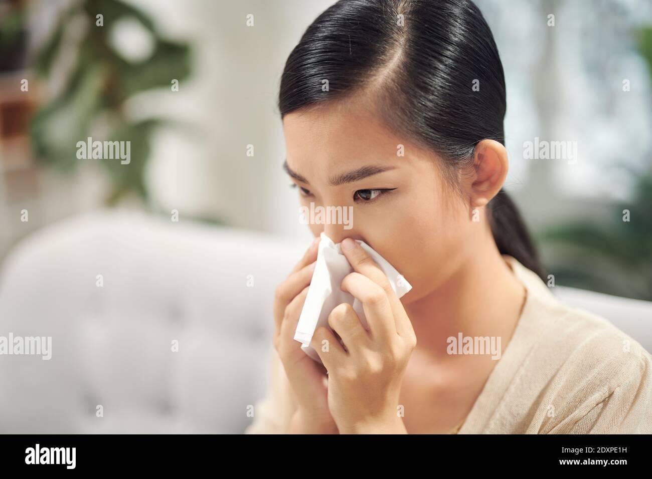 bella bella femmina adolescente cattura un freddo riposo sul divano e utilizzando carta per la pulizia del naso Foto Stock