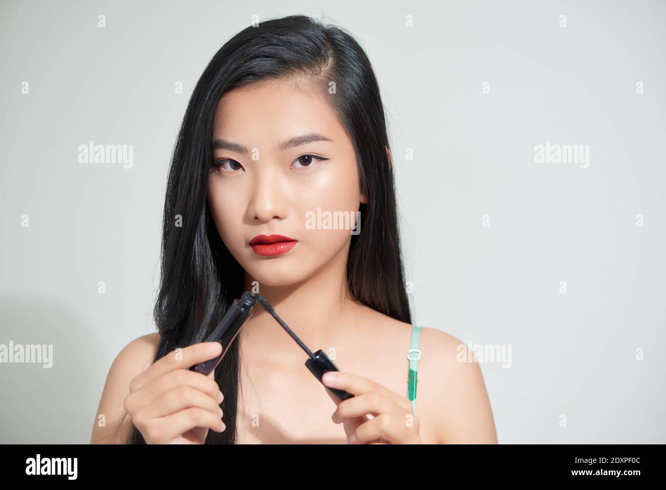 Ritratto di giovane bellissima femmina con spazzolino per mascara guardando la fotocamera Foto Stock